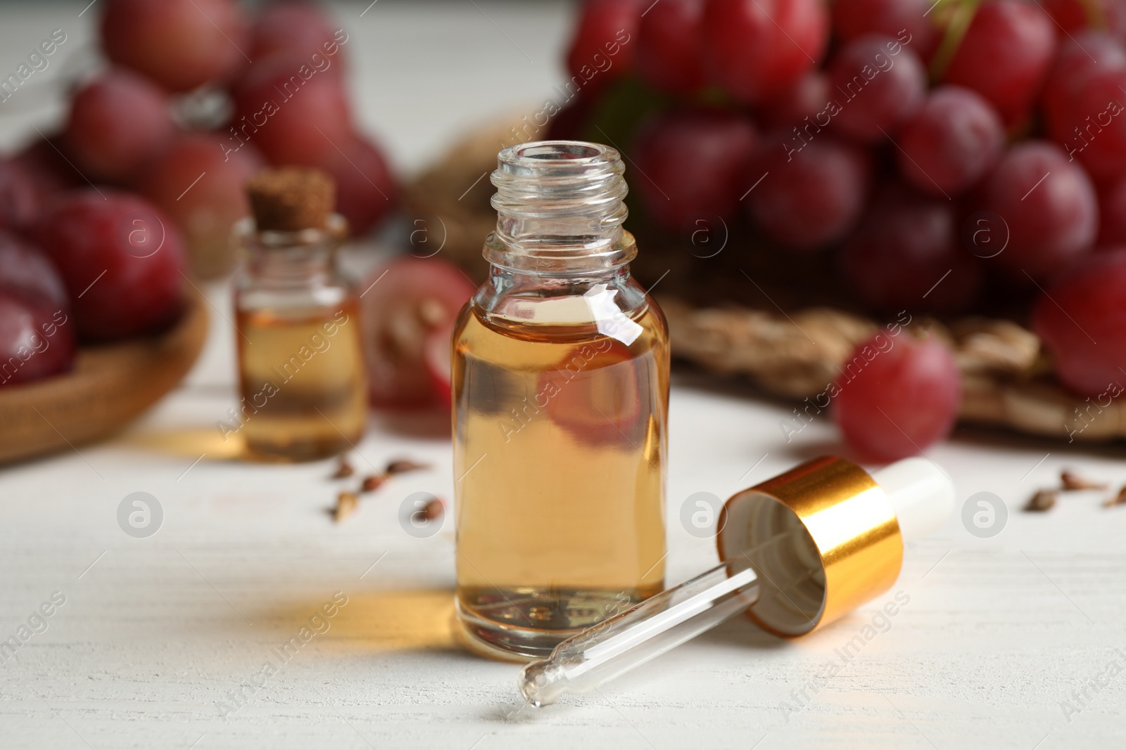 Photo of Bottle of natural grape seed oil on white wooden table. Organic cosmetic