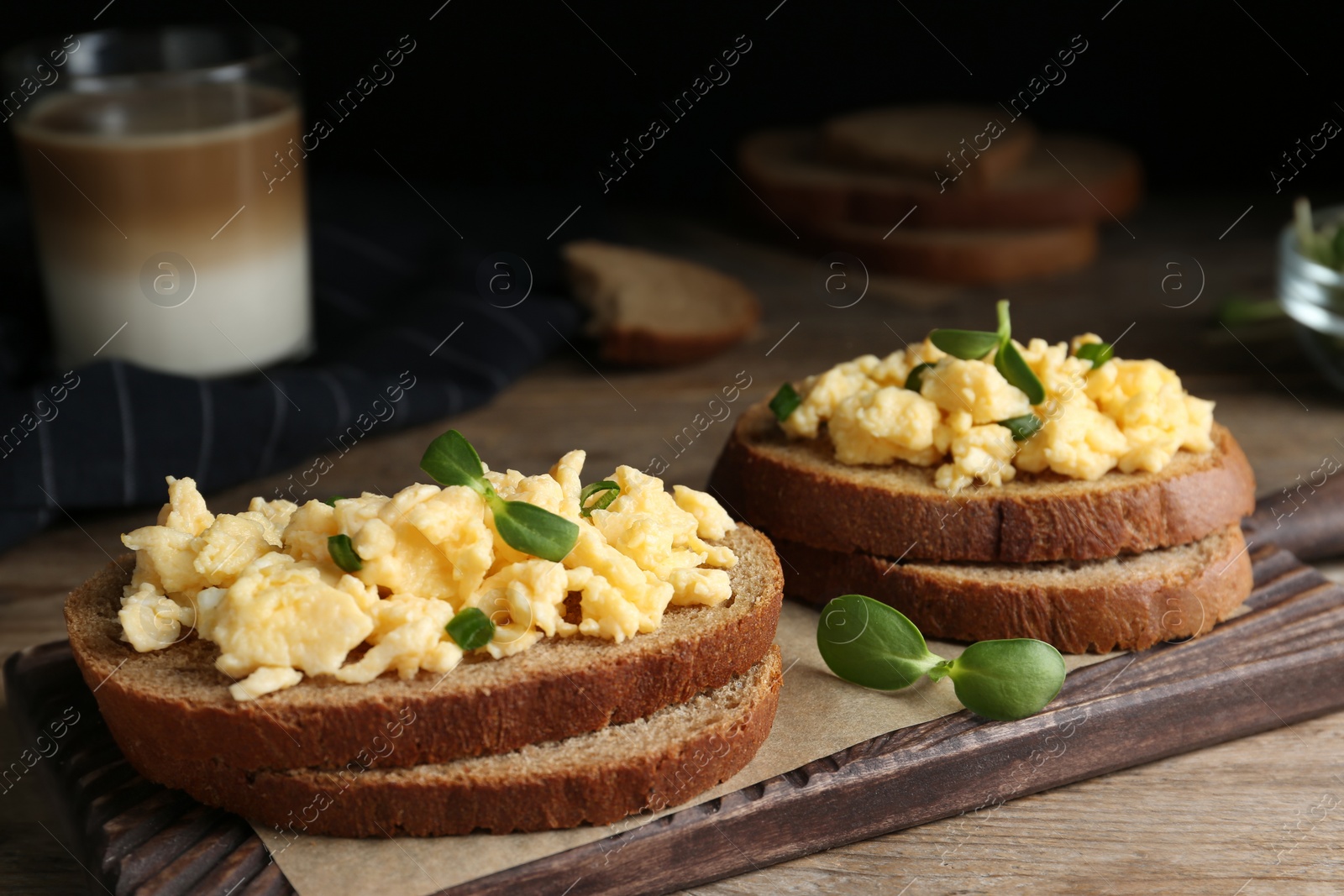 Photo of Tasty scrambled egg sandwiches on wooden board