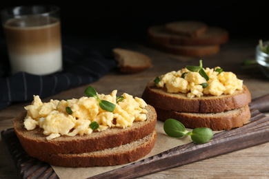 Tasty scrambled egg sandwiches on wooden board