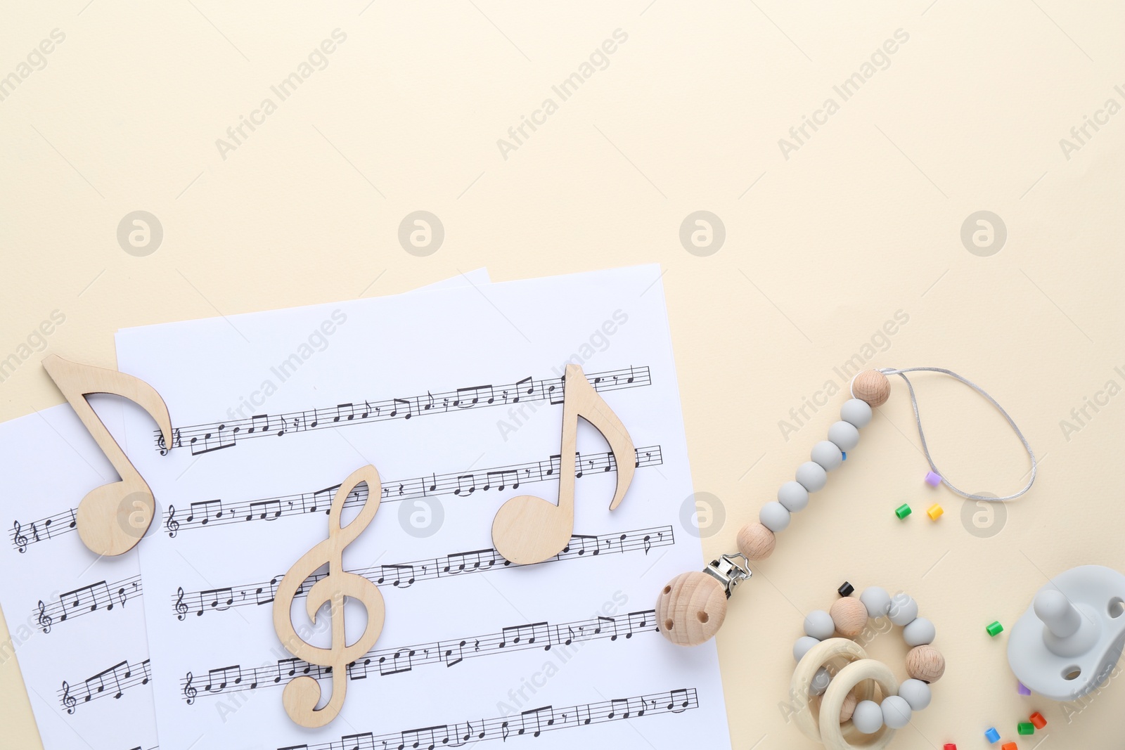 Photo of Wooden notes, music sheets and toys on beige background, flat lay with space for text. Baby song concept