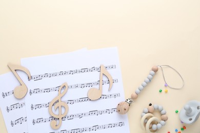 Wooden notes, music sheets and toys on beige background, flat lay with space for text. Baby song concept