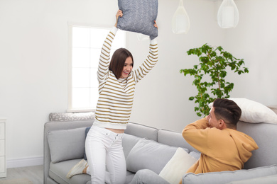 Happy couple having pillow fight in living room