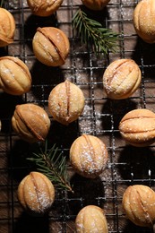 Delicious nut shaped cookies and fir branches on baking grid, flat lay