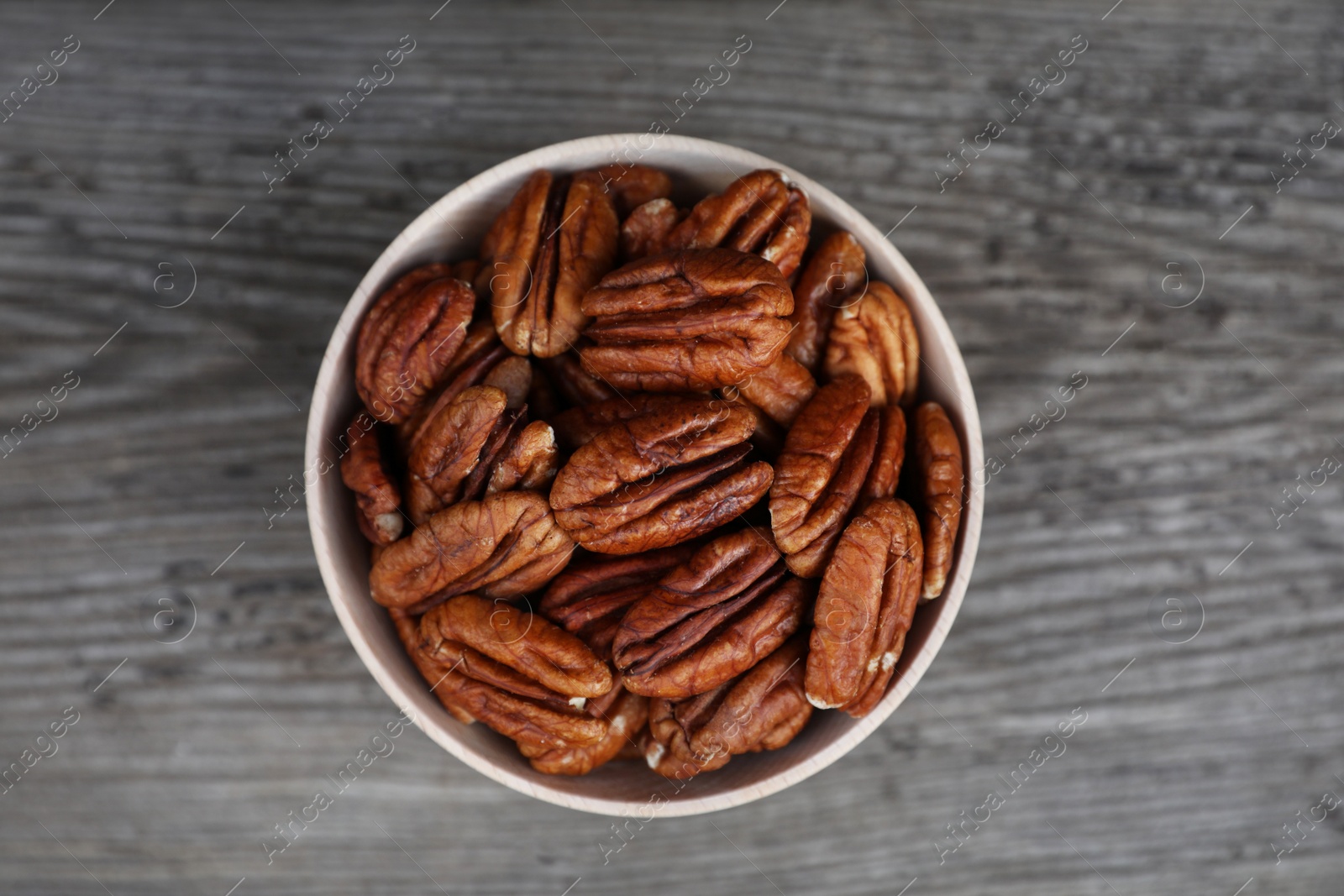 Photo of Tasty pecan nuts on grey wooden table, top view