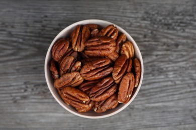 Photo of Tasty pecan nuts on grey wooden table, top view