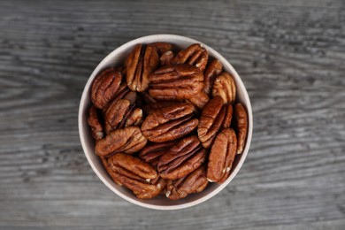 Tasty pecan nuts on grey wooden table, top view