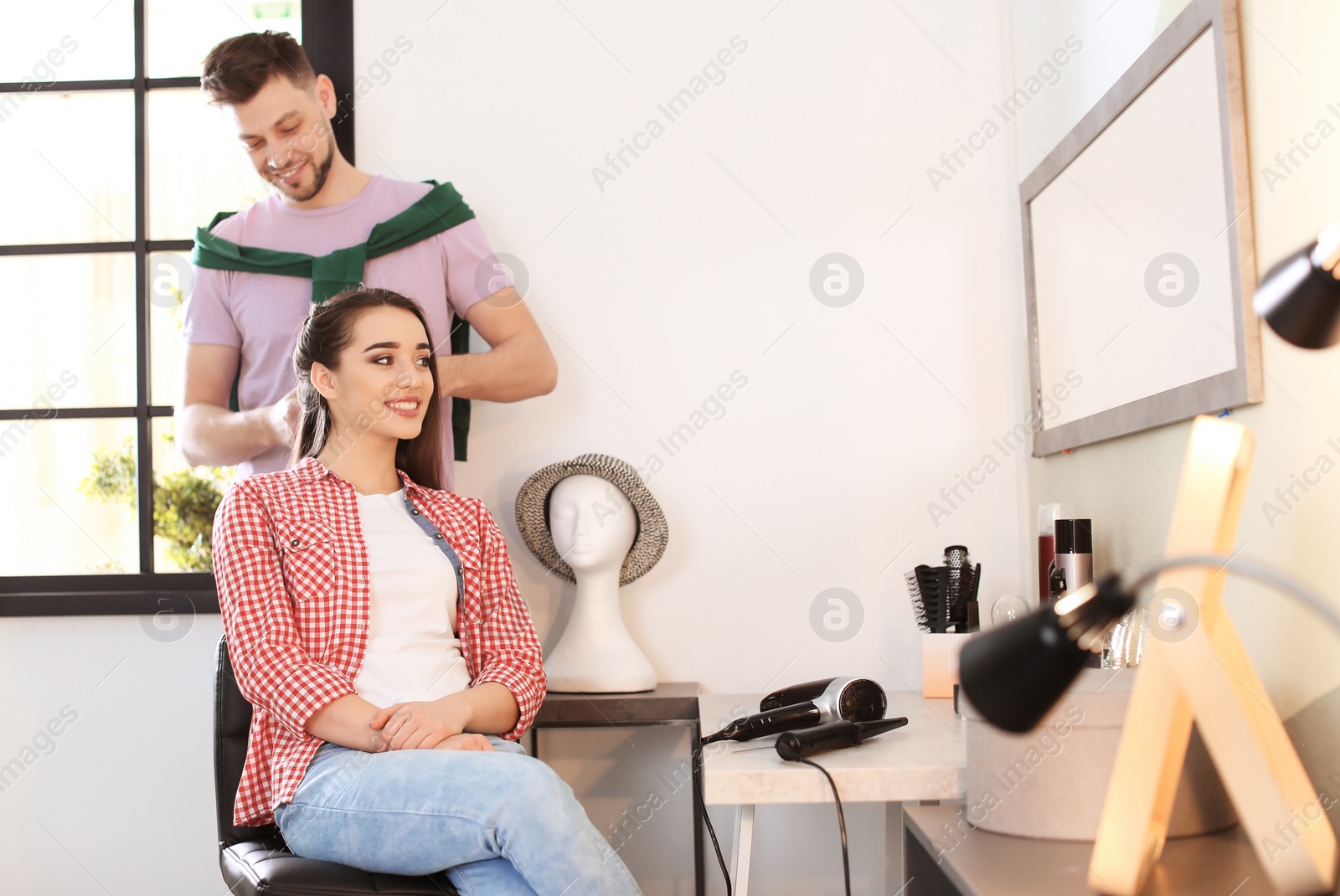 Photo of Professional hairdresser working with client in beauty salon