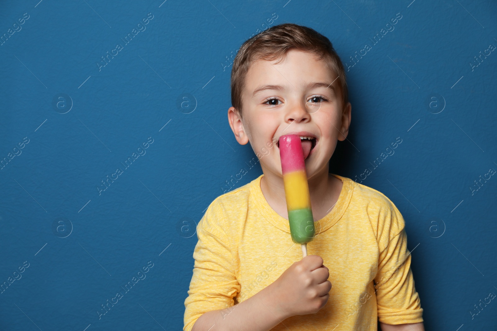 Photo of Adorable little boy with delicious ice cream against color background, space for text