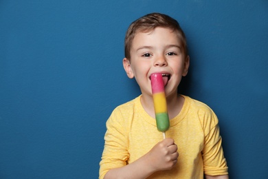 Photo of Adorable little boy with delicious ice cream against color background, space for text