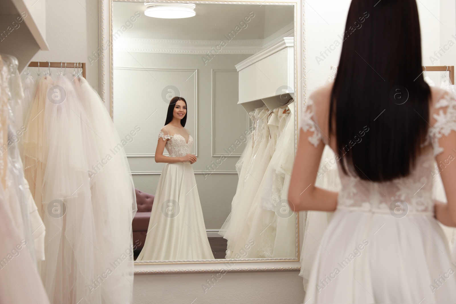 Photo of Woman trying on beautiful wedding dress in boutique