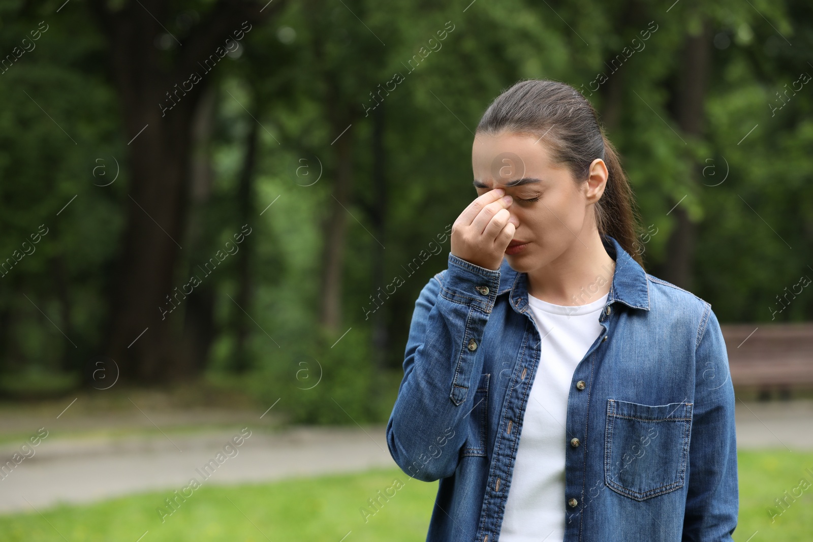 Photo of Woman suffering from seasonal spring allergy in park, space for text
