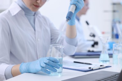 Photo of Scientist dripping sample into beaker in laboratory, closeup