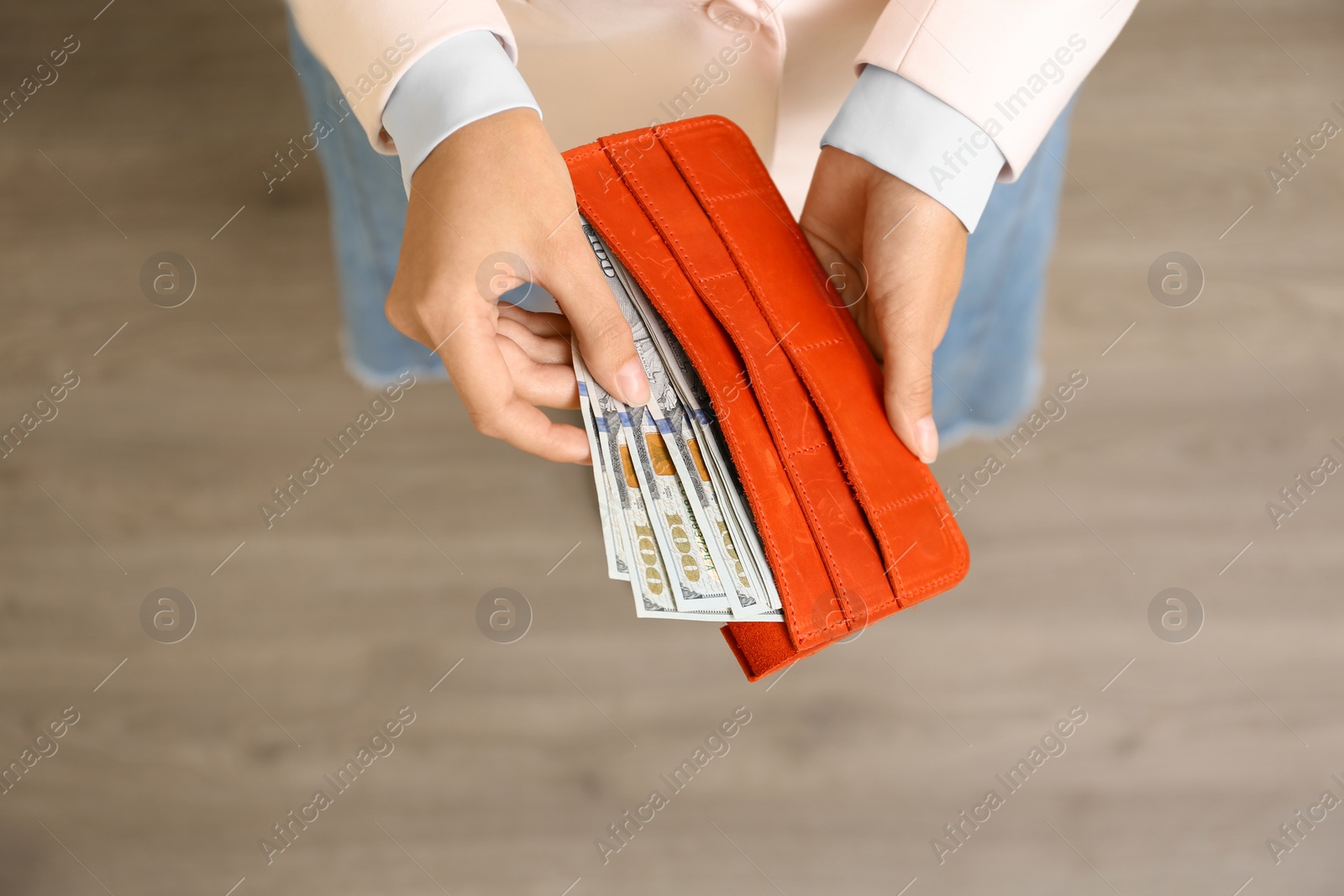 Photo of Young woman holding wallet with dollar bills, top view