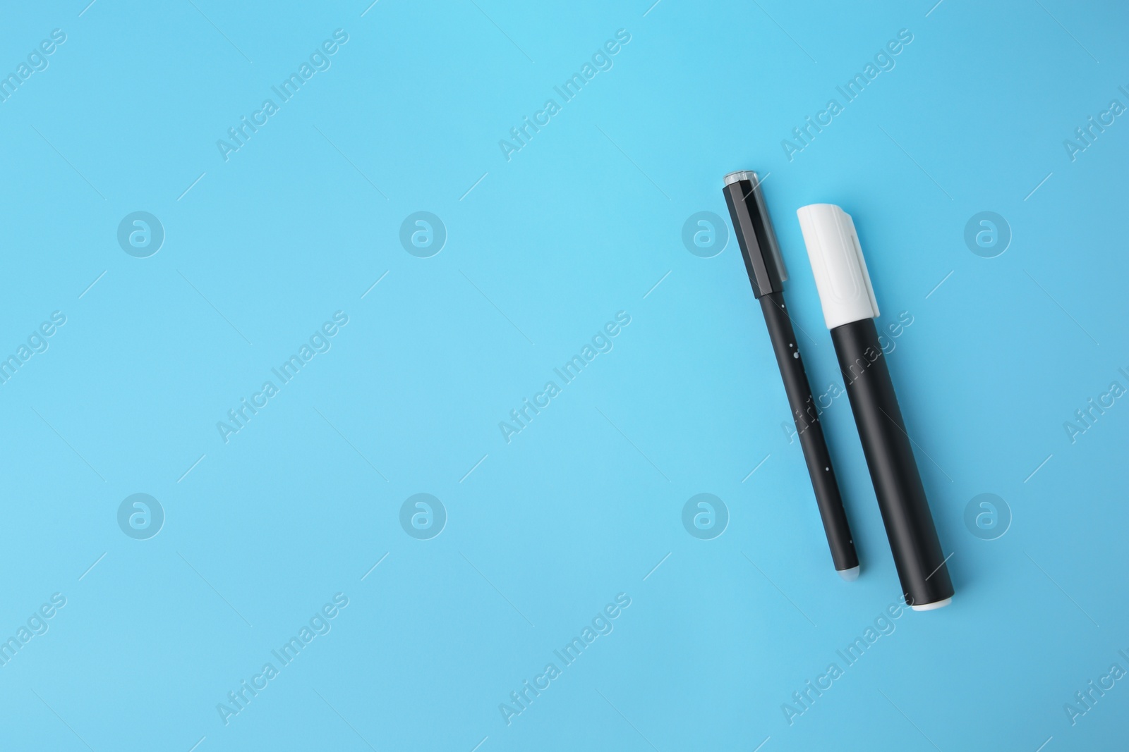 Photo of Erasable pen and marker on light blue background, flat lay. Space for text