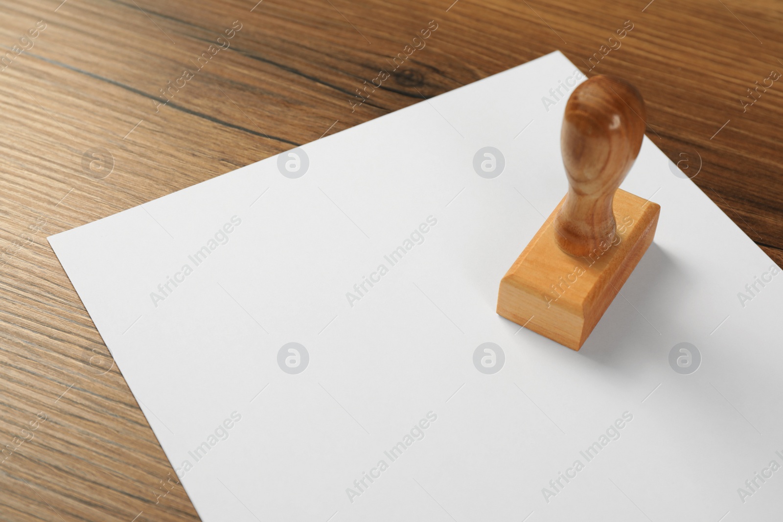 Photo of Blank sheet of paper and stamp on wooden table