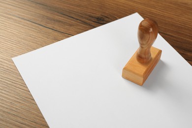 Photo of Blank sheet of paper and stamp on wooden table