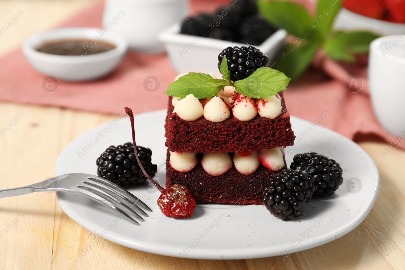 Photo of Piece of delicious red velvet cake with fresh berries served on wooden table, closeup