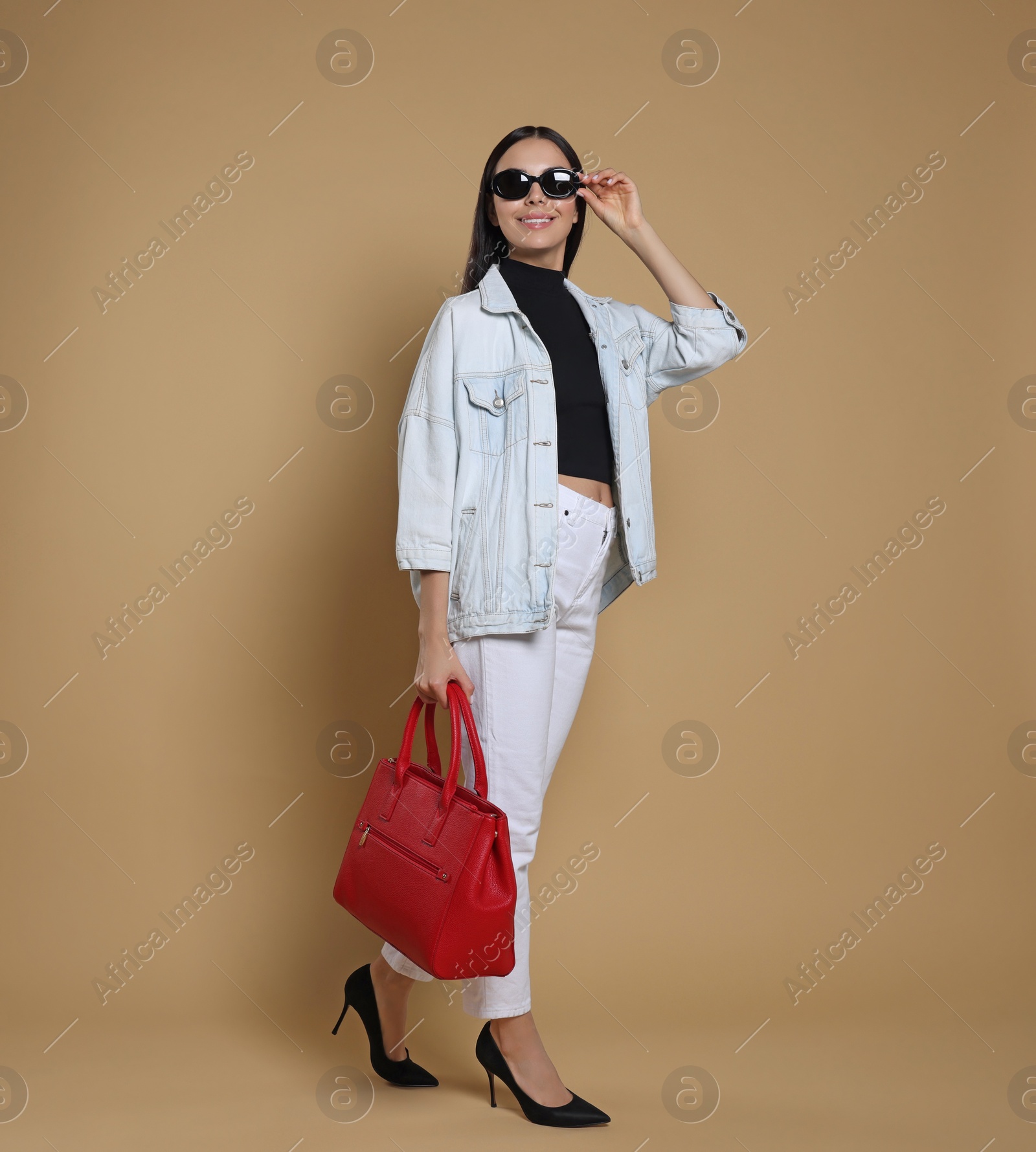 Photo of Young woman with stylish bag on beige background, space for text