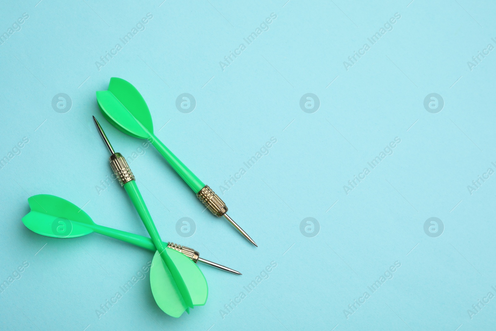 Photo of Green dart arrows on blue background, flat lay with space for text