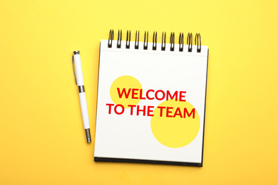 Image of Notebook with phrase Welcome to the team and pen on yellow background, top view