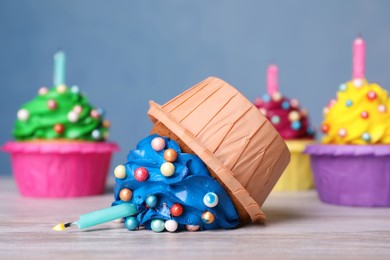 Photo of Dropped cupcake among good ones on white wooden table, closeup. Troubles happen