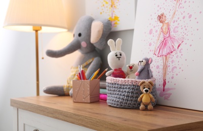 Photo of Stationery, picture and toy on wooden chest of drawers in children's room. Interior design