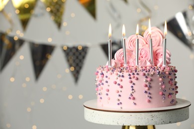Photo of Beautifully decorated birthday cake on stand against blurred festive lights. Space for text