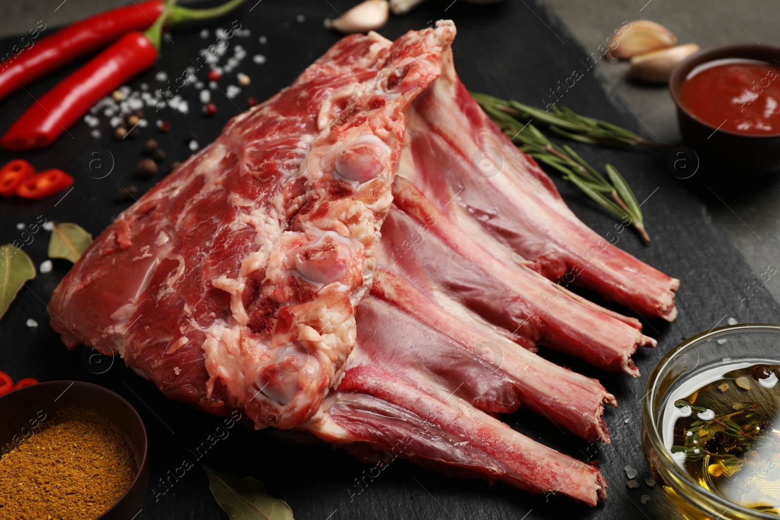 Photo of Raw ribs with spices on slate board, closeup