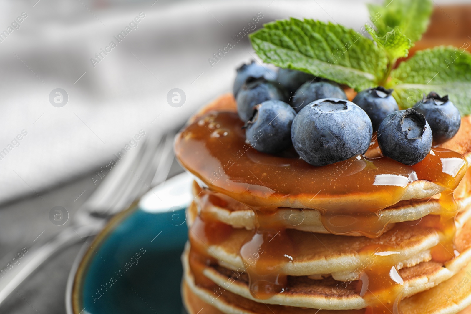 Photo of Delicious pancakes with fresh blueberries and syrup on table, closeup
