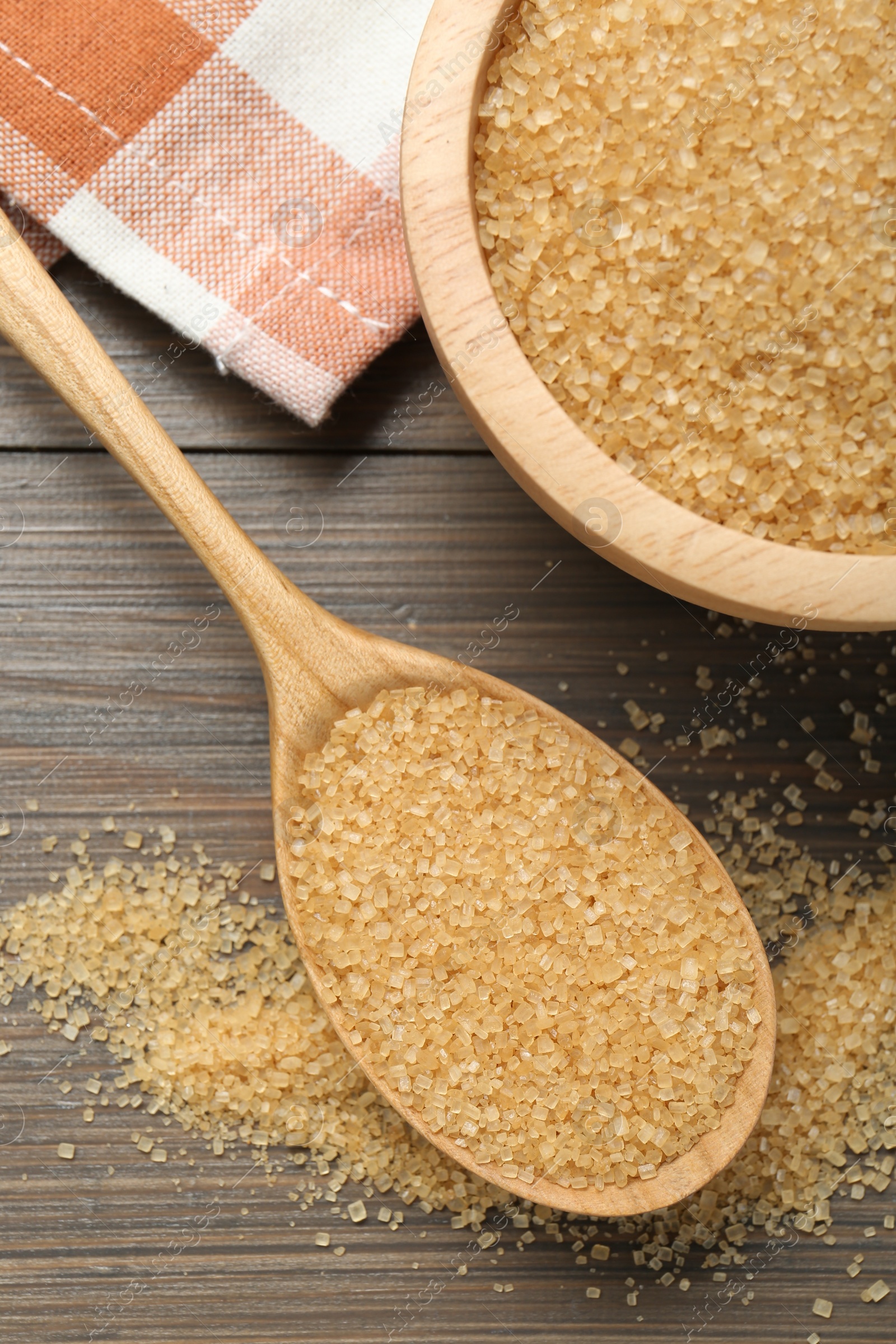 Photo of Brown sugar in bowl and spoon on wooden table, flat lay