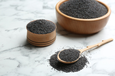 Poppy seeds in bowls and spoon on white marble table