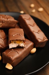 Photo of Plate of chocolate bars with caramel, nuts and nougat on table, closeup