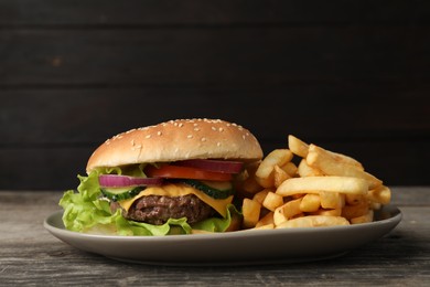 Photo of Delicious burger and french fries served on wooden table