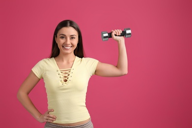 Photo of Woman with dumbbell as symbol of girl power on pink background, space for text. 8 March concept