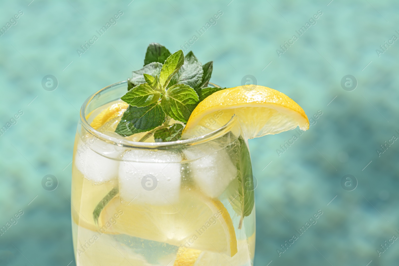 Photo of Refreshing drink with citrus slices and mint on blurred background, closeup