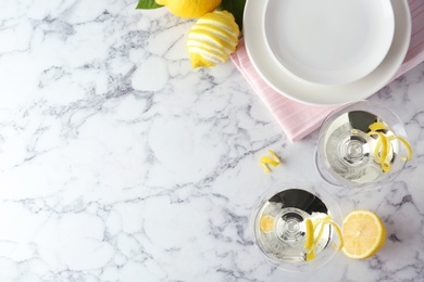 Photo of Flat lay composition of lemon drop martini cocktails with zest on white marble table. Space for text