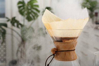 Photo of Making drip coffee. Glass chemex coffeemaker with paper filter indoors, closeup. Space for text