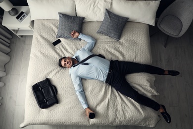 Photo of Exhausted businessman in office wear sleeping on bed at home after work, above view