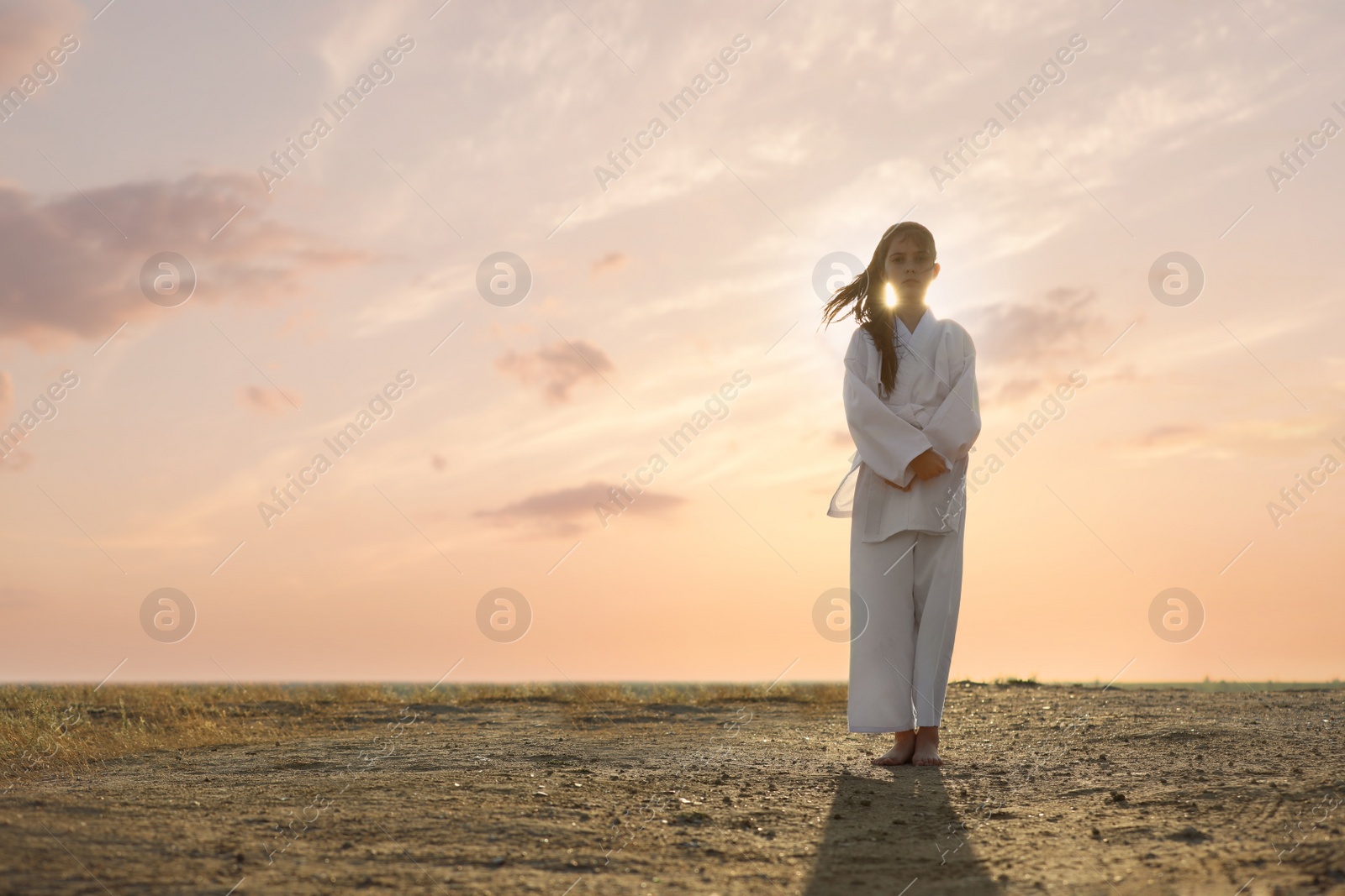 Photo of Cute little girl in kimono practicing karate outdoors