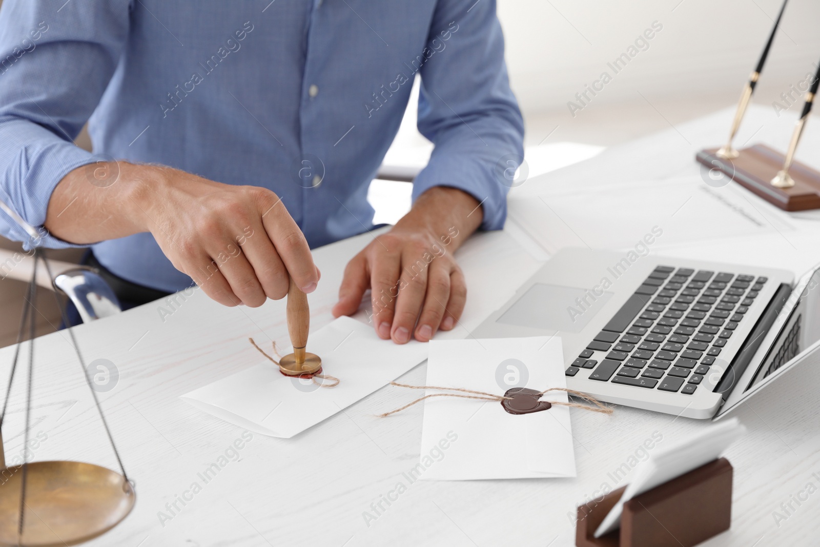 Photo of Male notary stamping document at table in office, closeup