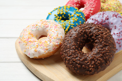 Photo of Yummy donuts with sprinkles on white wooden table, closeup