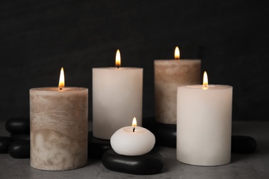 Photo of Burning candles and spa stones on grey table