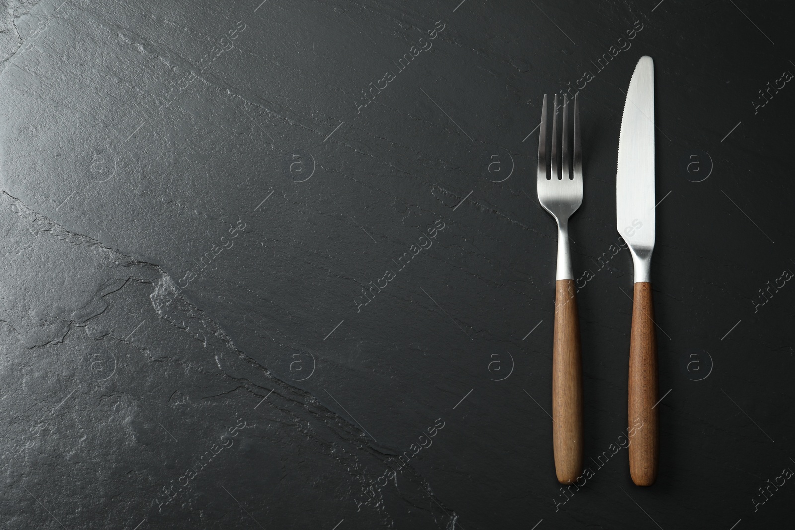 Photo of Stylish cutlery on black table, top view. Space for text