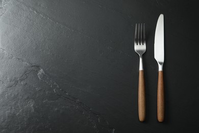 Stylish cutlery on black table, top view. Space for text