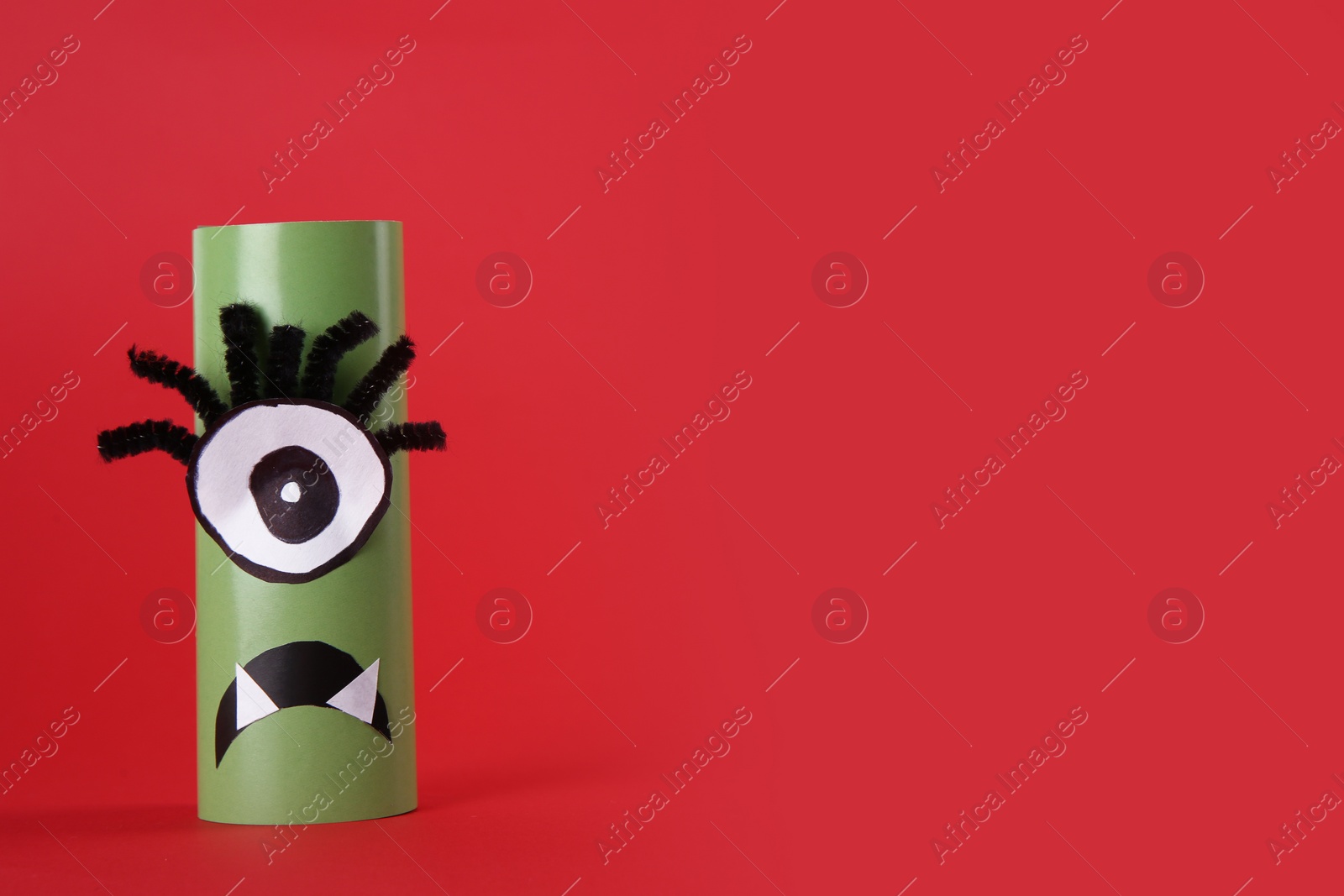 Photo of Funny green monster on red background, space for text. Halloween decoration