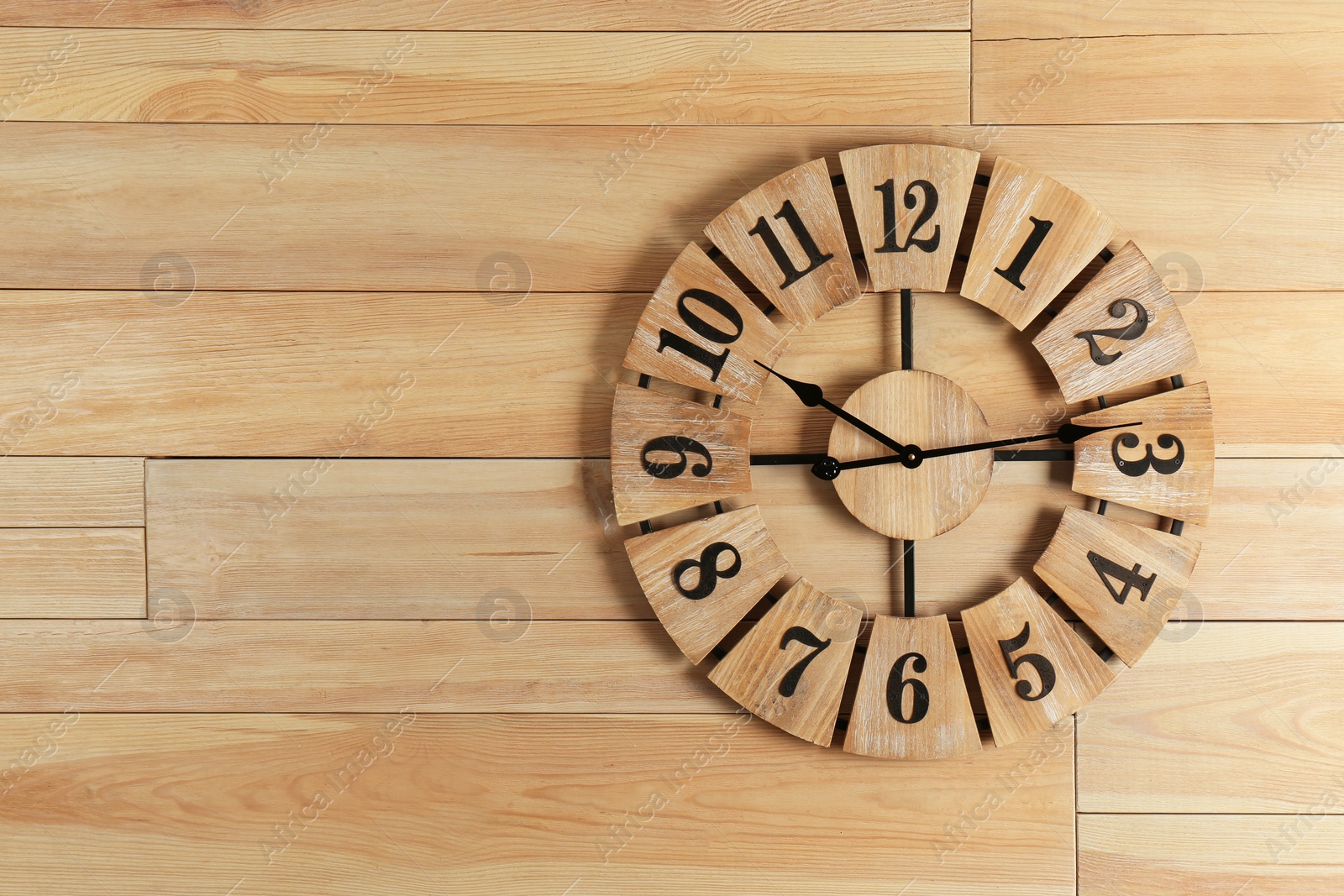 Photo of Stylish analog clock hanging on wooden wall. Space for text