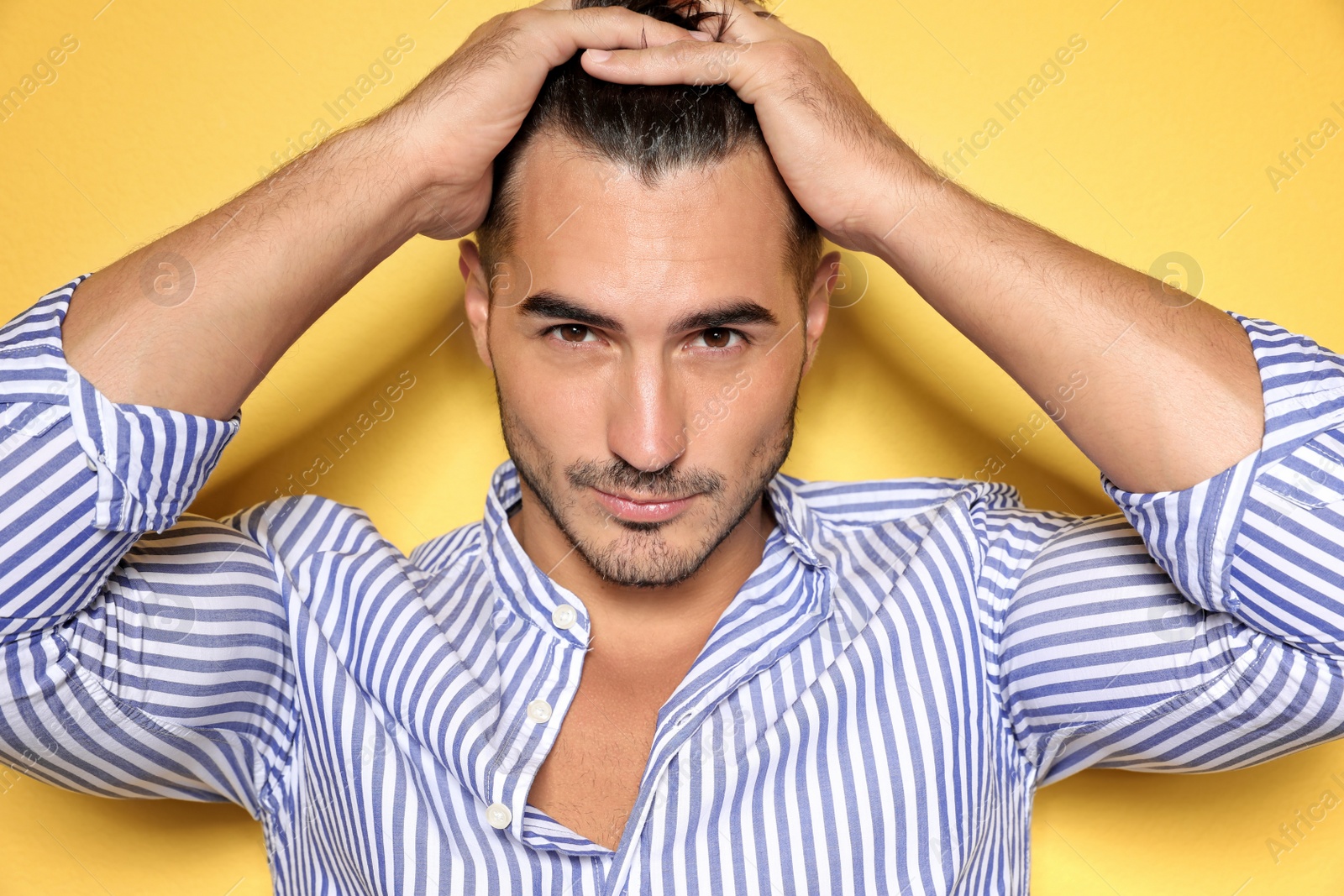 Photo of Young man with trendy hairstyle posing on color background