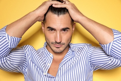 Photo of Young man with trendy hairstyle posing on color background