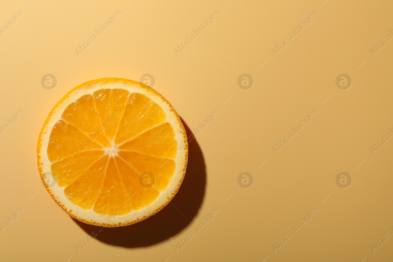 Photo of Slice of juicy orange on beige background, top view. Space for text