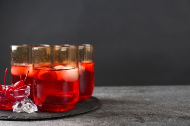 Photo of Delicious strawberry cocktails served with ice balls and cherries on grey table, space for text